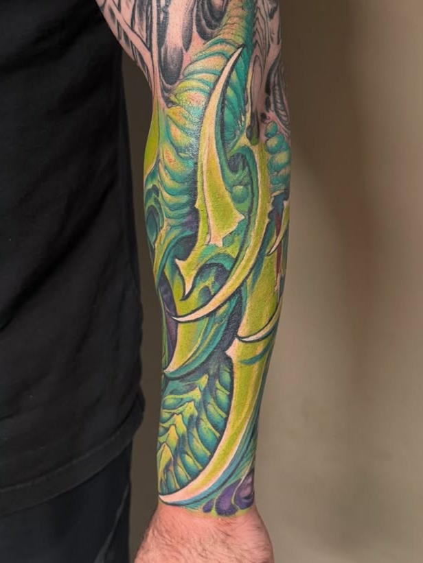 blade and abstract shape biomechanical style tattoo by Ron Earhart